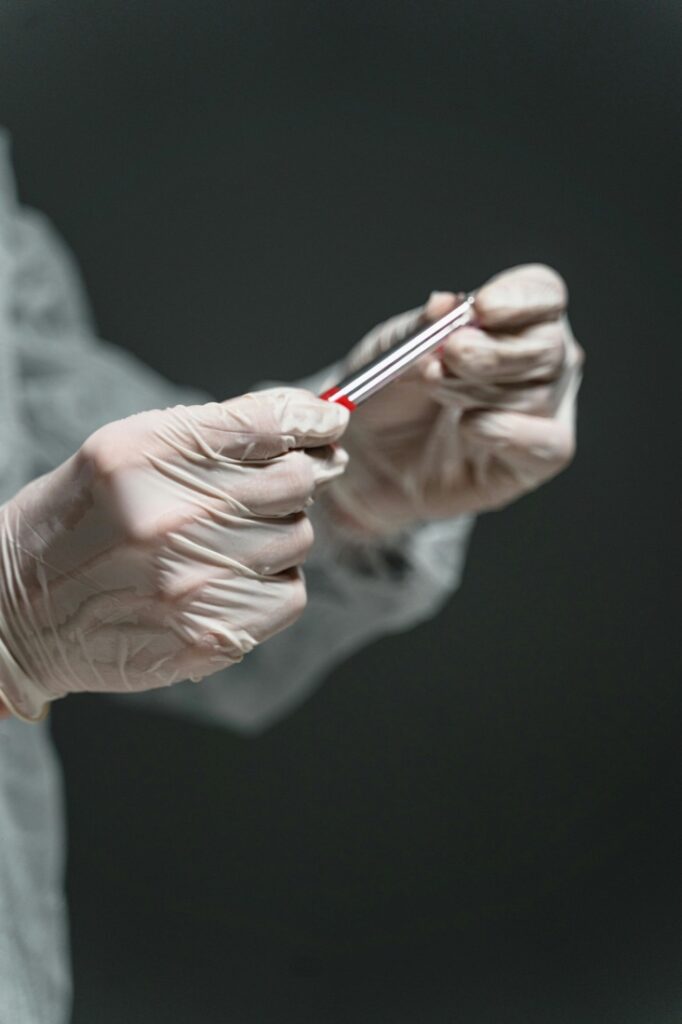 Clinician handling a blood sample vial in gloved hands